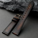 Brown leather watch strap on a dark gray surface with a stone background, Obroi