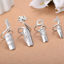 Set of silver rings with intricate designs on a beige surface, Obroi