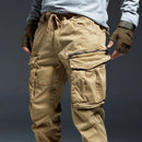 Person wearing beige tactical pants with a dark background, Obroi