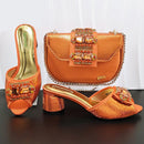 Orange high-heeled shoes and matching handbag with embellishments on a dark surface, Obroi