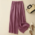 Purple pants with lace trim on a beige background, accompanied by a straw bag and white shoes, Obroi