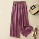 Purple pants with lace trim on a beige background, accompanied by a straw bag and white shoes, Obroi