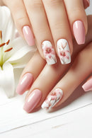 Nails with floral design and pink polish held against a white flower background, Obroi
