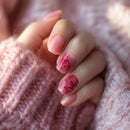 Hand with pink floral nail design wearing a pink knitted sweater, Obroi