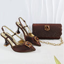 A women's fashion accessory set including a pair of brown pointed-toe slingback high heels and a matching brown rhinestone-embellished clutch bag with a gold chain strap, displayed on a white draped fabric background. The brand name 'Obroi' is visible in the top left corner.