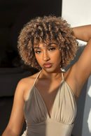 Woman with curly hair wearing a beige halter top against a blurred background, Obroi