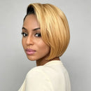 A woman with a short, layered blonde bob wig shown from the back-three-quarter angle against a plain light gray studio background, Obroi