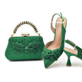 Green handbag and high-heeled shoes with floral details on a white background, Obroi