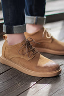 Brown leather shoes worn with rolled-up jeans on a wooden floor, Obroi