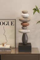 Stacked stone sculpture on a table with a 'Obroi' magazine in the background, Obroi