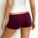 Person wearing purple shorts and a white top on a plain background, Obroi