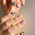 Hand with cow print and floral nail designs on a neutral background, Obroi