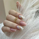 Hand with pink and gold nail design wearing a gold ring on a soft background, Obroi