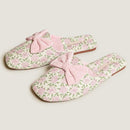 Pair of floral slippers with pink bows on a light background, Obroi