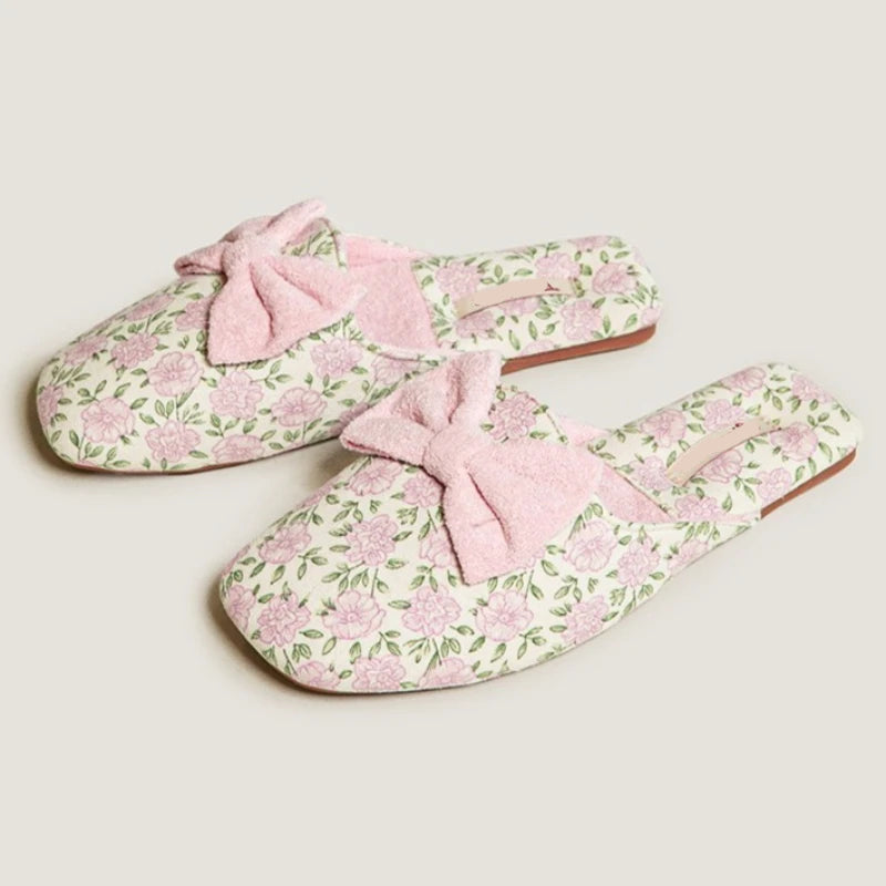 Pair of floral slippers with pink bows on a light background, Obroi