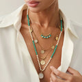 Woman wearing multiple necklaces with green beads and gold accents, Obroi