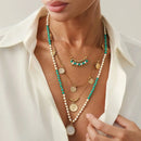 Woman wearing multiple necklaces with green beads and gold accents, Obroi