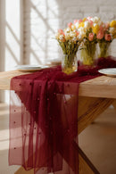 Table setting with a red table runner, white plates, and floral arrangements in clear vases, Obroi