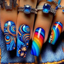 Colorful nail art on a person's hand with blue gemstone rings, Obroi