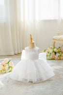 White children's dress on a mannequin with floral decorations in the background, Obroi