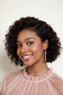 Woman with curly hair wearing a pink top against a plain background, Obroi