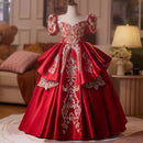 Red evening gown with gold embroidery on a mannequin in a room setting, Obroi
