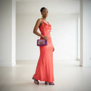 Woman in a coral dress holding a purple handbag in a minimalistic setting, Obroi