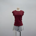 A short-sleeve crewneck t-shirt in burgundy with a small black polka dot pattern, displayed on a mannequin torso paired with light-wash denim shorts against a neutral gray background, Obroi