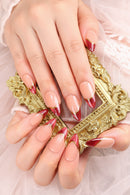 Close-up of hands with red and beige nail design against a gold ornate background, Obroi