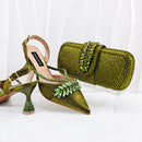 Green high-heeled shoes with embellishments and a matching clutch on a white background, Obroi