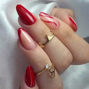 Hand with red nail polish wearing two gold rings on a white background, Obroi