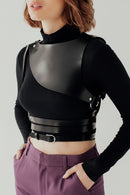 Person wearing a black leather outfit with a high collar and belt on a plain background, Obroi