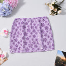 Purple floral sequin skirt on a light gray surface with flowers and a photo album around, Obroi