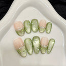 Set of decorative nails with green and pink design on a white surface, Obroi