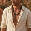 Man wearing a beige shirt with a necklace in a natural setting, Obroi