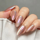 A close-up of a hand with almond-shaped nails painted in a shimmery iridescent pink nail polish that shifts with light, resting against a white fabric surface, Obroi