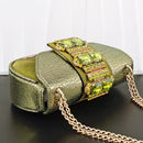 Green handbag with gemstone embellishments on a dark surface, Obroi