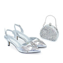 Obroi Silver high-heeled shoes with embellishments and a matching handbag on a white background.