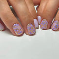 Close-up of hands with pink and purple floral nail design on a white background, Obroi