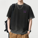Person wearing a black t-shirt with a purple logo, tan pants, and a black backpack on a light gray background, Obroi