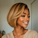 A smiling woman with a short layered bob wig in warm blonde and brown tones, wearing a beige top and gold hoop earrings in an indoor setting, Obroi