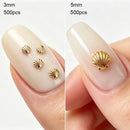 Two close-up views of a fingernail displaying small gold shell-shaped nail decorations. The left side shows four 3mm shells on a nude manicured nail, with text reading '3mm 500pcs', Obroi