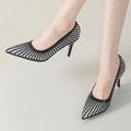 Black mesh high-heeled shoes worn by a person on a light gray background, Obroi