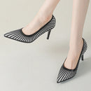 Black mesh high-heeled shoes worn by a person on a light gray background, Obroi