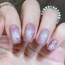 Close-up of a hand with pink floral nail design and silver rings, Obroi