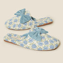 Pair of floral slippers with blue bows on a beige background , Obroi
