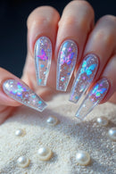 A close-up of a hand showcasing coffin-shaped press-on nails with a clear acrylic base decorated with colorful butterfly and star designs, Obroi