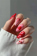 Hand with red and pink nail art on a neutral background, Obroi