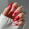 Hand with red and pink nail art on a neutral background, Obroi