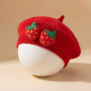 Red beret with strawberry decorations on a beige background, Obroi